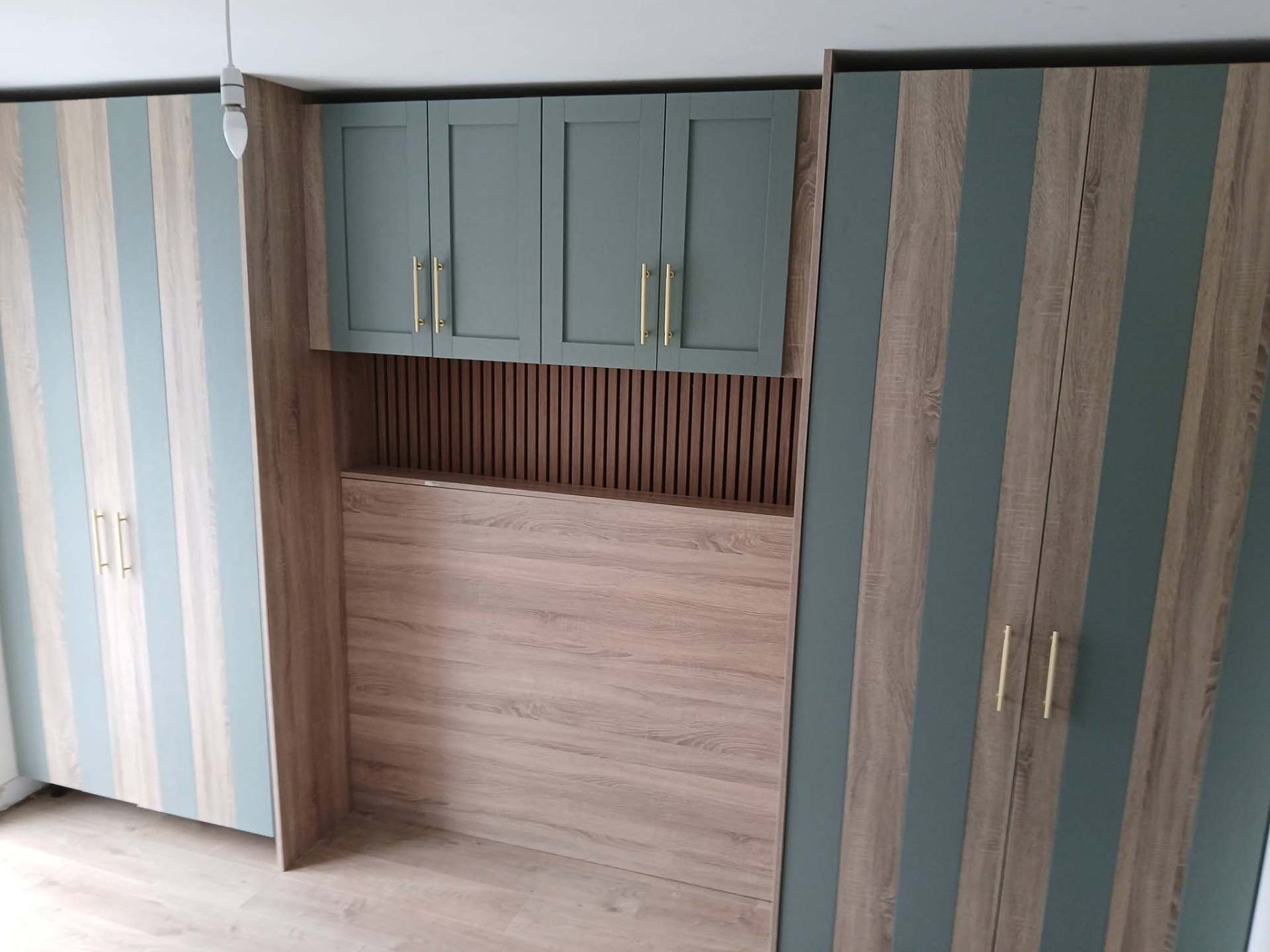 Sage green and oak fitted bedroom wardrobes with slatted panel nook and brass handles